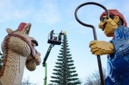 Legoland model maker Katrina James (R) placing a Lego star onto the top of a 8m tall Lego Christmas tree during a photocall at Legoland Windsor Resort, west of London ©AFP PHOTO / LEON NEAL