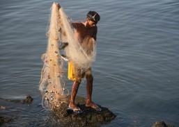A fisherman walks carefully near the Manila Bay breakwater off Roxas Blvd., carrying his net with a meager catch of tilapia fish on Friday (Jan. 3, 2014). (MNS photo)